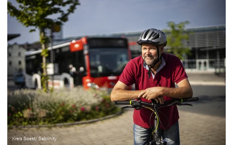 Mann steht mit Fahrrad vor Fahrradbus